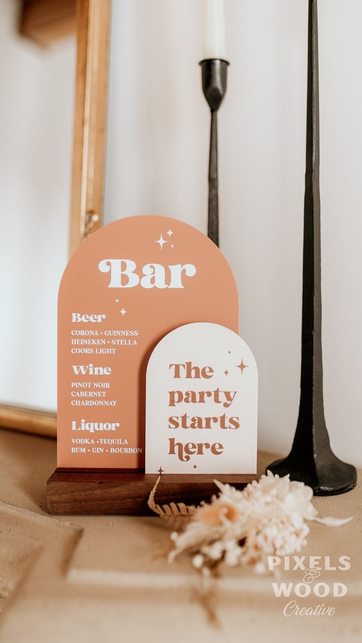 a bar sign sitting on top of a wooden table next to a candle and mirror