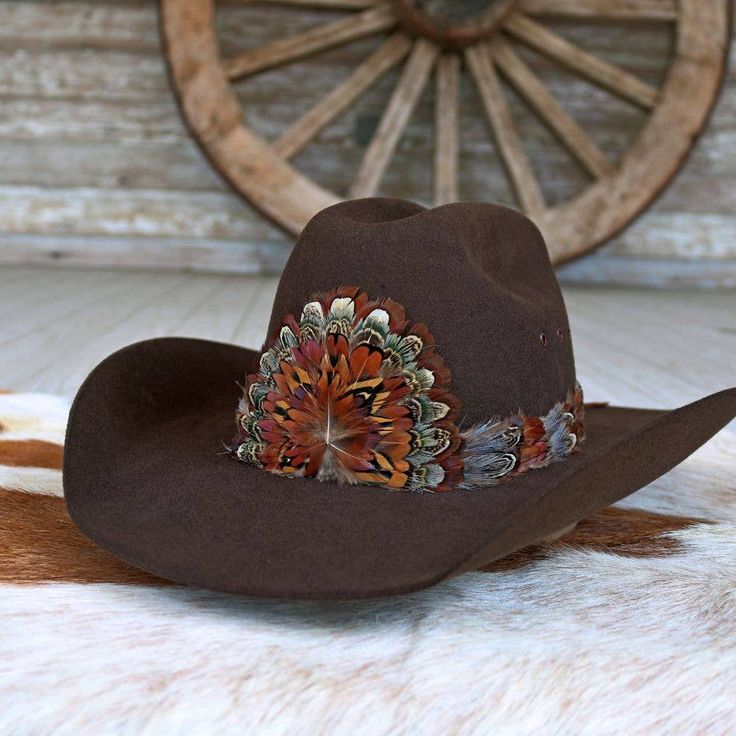 The Rowan Western Feather Hat Band, Short, is specially crafted for smaller-sized hats (6 7/8 and under) and kids' hats. Made from 100% feather, it has an approximate length of 53 cm (excluding leather ties) and a width of 2 cm. The crest measures 4" W x 3.25" H, adding a distinctive and elegant touch to the design. Adjustable with leather ties, this hat band ensures a secure fit while providing a stylish western accent for smaller hats. Brown Hat Bands With Feathers For Western-themed Events, Brown Hats With Feathers For Country Events, Brown Country Hat With Feathers, Brown Feathered Hat For Country Events, Country Style Brown Hat With Feathers, Brown Feathered Country Hat, Brown Hat Bands With Feathers For Western Events, Brown Hat With Feather Trim For Country Events, Brown Top Hat For Country Events With Short Brim