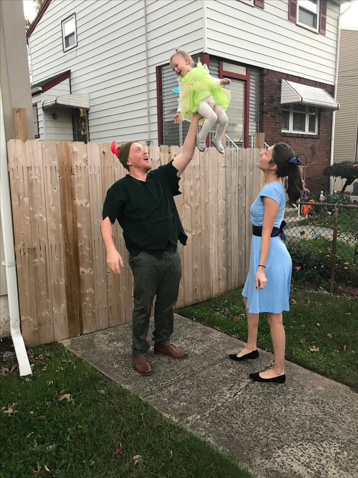 a man holding up a stuffed animal in the air next to a woman on a sidewalk