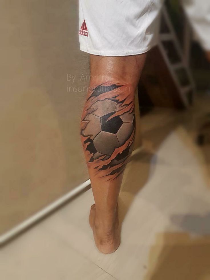 a man with a tattoo on his leg has a soccer ball coming out of it