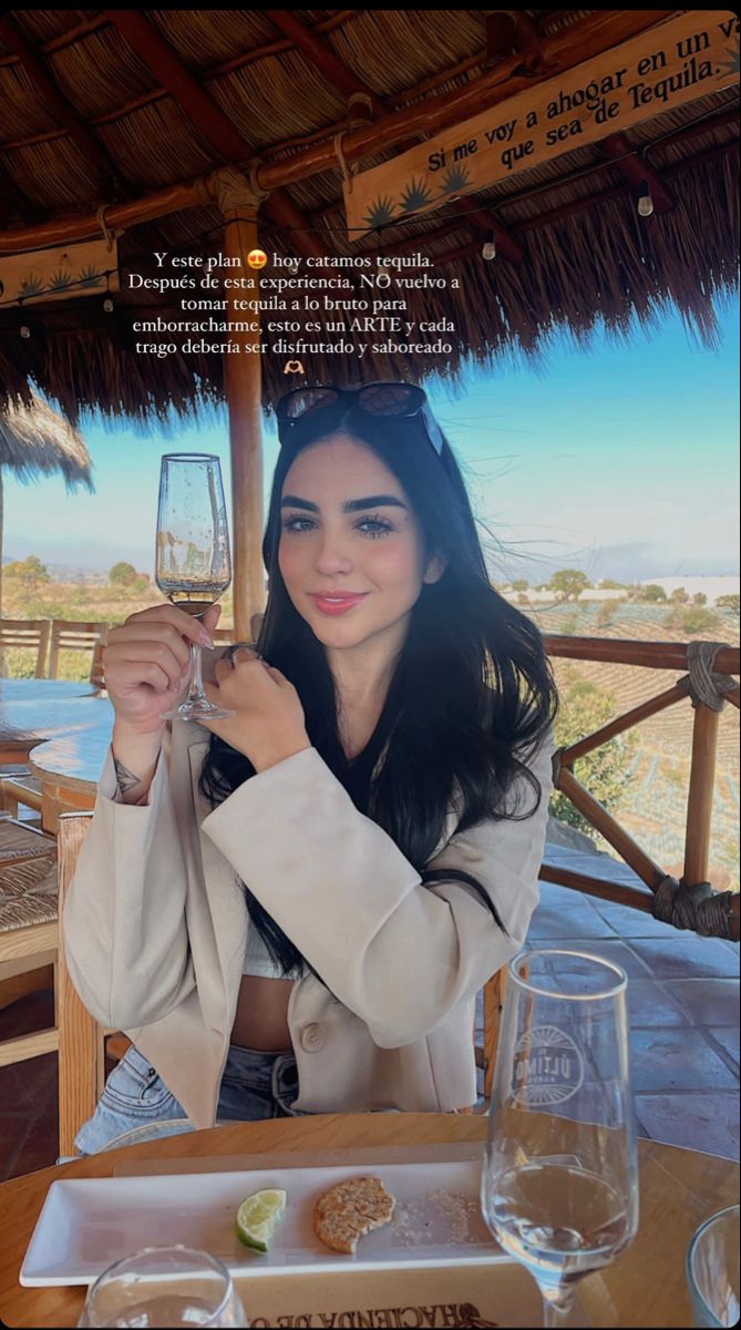 a woman sitting at a table with a glass of wine