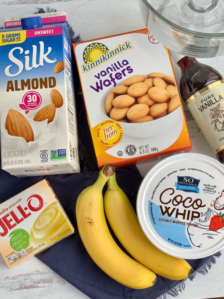 some food is laying out on a table with milk, yogurt, almonds and bananas