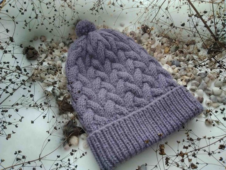 a purple knitted hat laying on top of dry grass