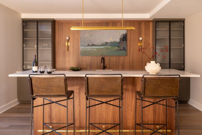 a kitchen with three bar stools and a painting on the wall