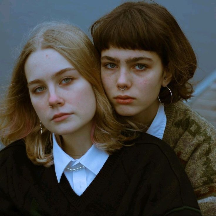 two young women sitting next to each other, one with her head on the shoulder