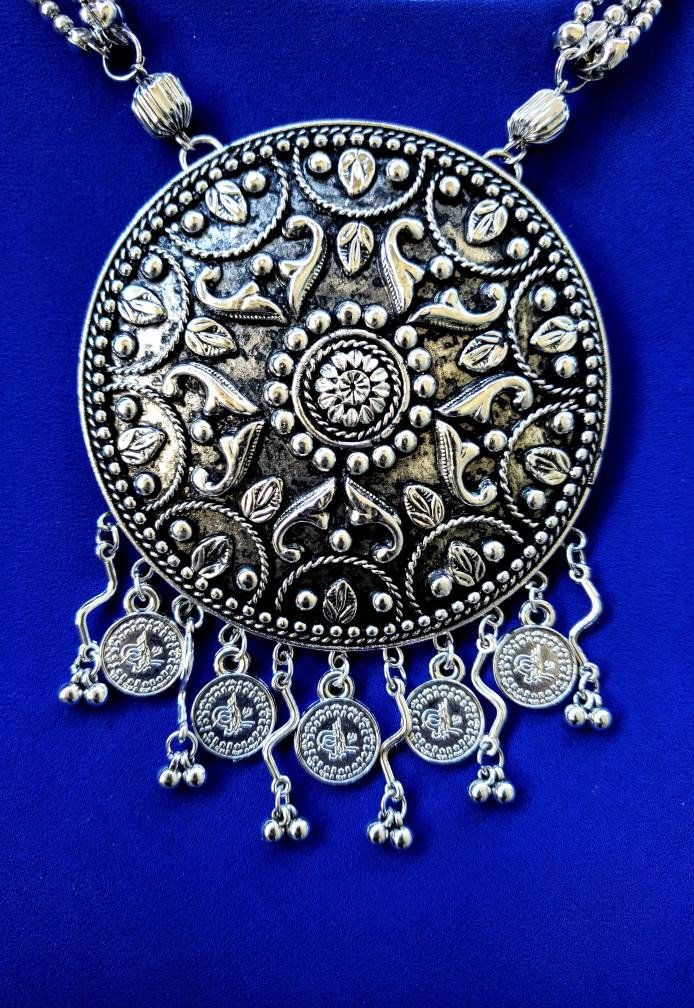 Dramatic Afghani tribal pendant necklace with round stud earrings, in German silver, to recreate the patina of a vintage tribal piece. it has a lovely soft glow to it. Beautiful embossed mandala medallion is an embossed mandala, that has a soft glow to it due to the textured finish and some blackening of the details, to bring out the intricate details. Little leaf motifs along the edge are repeated in the matching stud earrings. Medallion is suspended from 4 strand bead necklace, with interestin Round Coin Pendant Jewelry For Festivals, Round Festival Coin Pendant Jewelry, Festival Coin Pendant Jewelry, Diwali Jewelry With Intricate Round Pendant, Silver Round Pendant Necklace For Diwali, Traditional Handmade Round Medallion Necklace, Filigree Metal Chandbali Jewelry, Metal Filigree Chandbali Jewelry, Navratri Jewelry With Intricate Metal Design