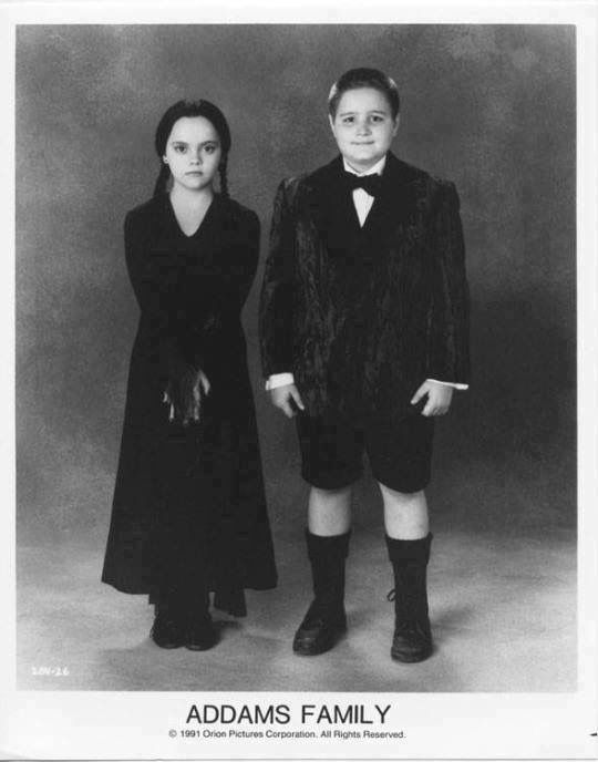 an old black and white photo of two children dressed in formal clothing, standing next to each other