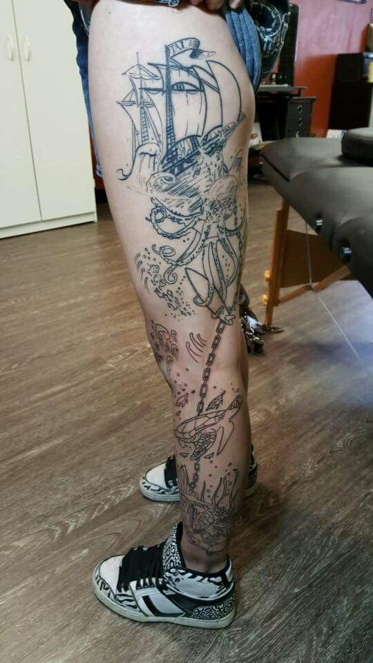 a man's leg with tattoos on it and a ship in the middle of his leg