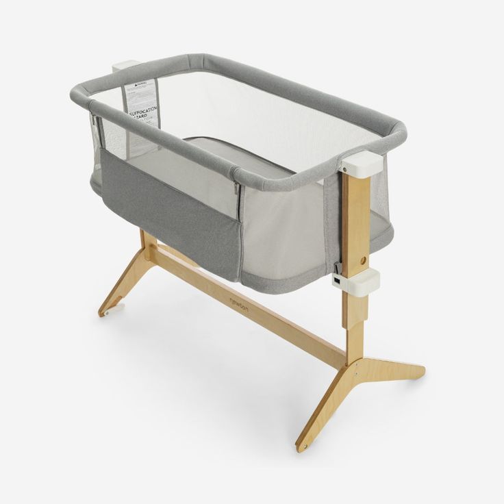 a baby crib with a wooden frame and grey fabric in the front, on a white background