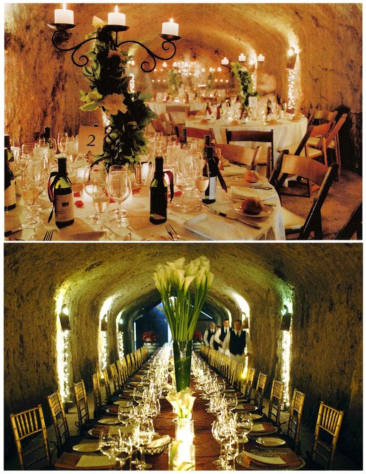 there are many tables and chairs set up in this cave like setting with candles on each table