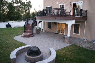 a patio with a fire pit in the middle and stairs leading to an upper level deck