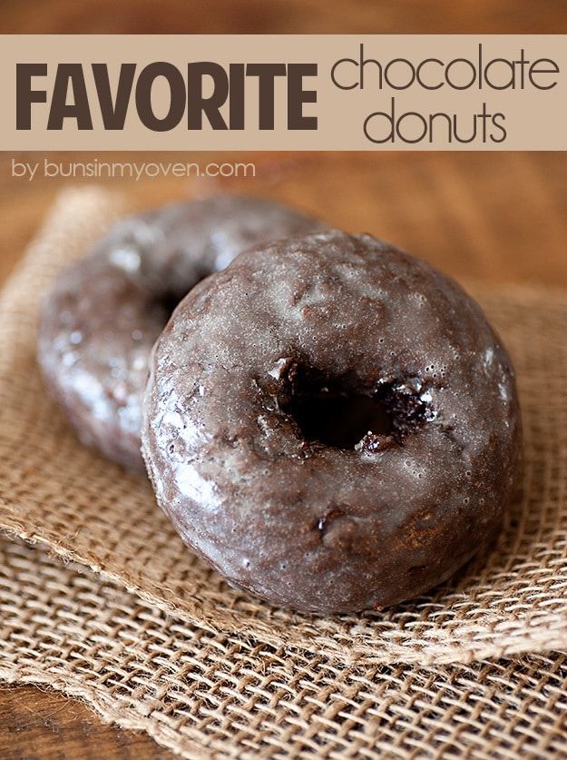 two chocolate donuts sitting on top of a brown cloth