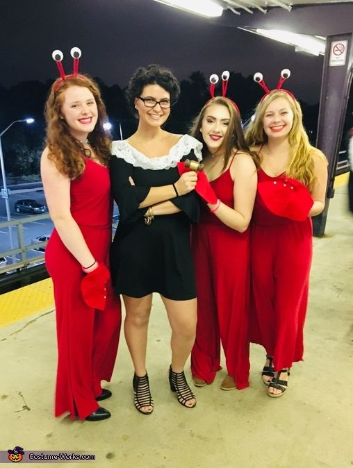 four women dressed in red and black posing for the camera with lady bugs on their heads