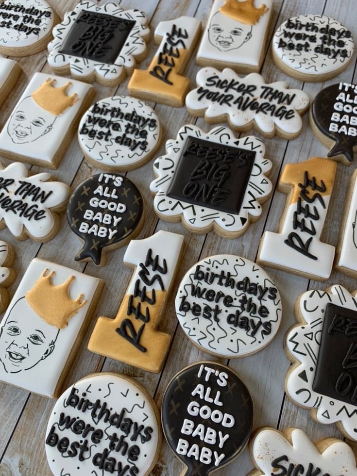 decorated cookies with black and white icing are arranged on a wooden table, including baby ones