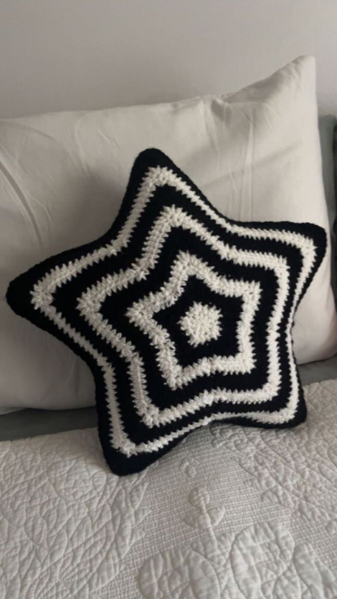 a black and white crocheted star pillow on a bed