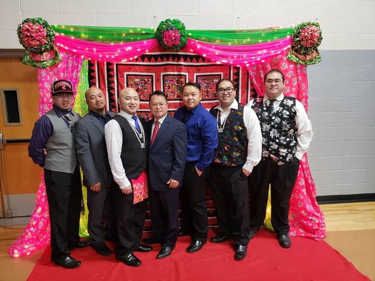 a group of men standing next to each other in front of a red and green backdrop