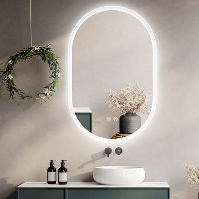 a bathroom with a sink, mirror and plants on the counter top in front of it