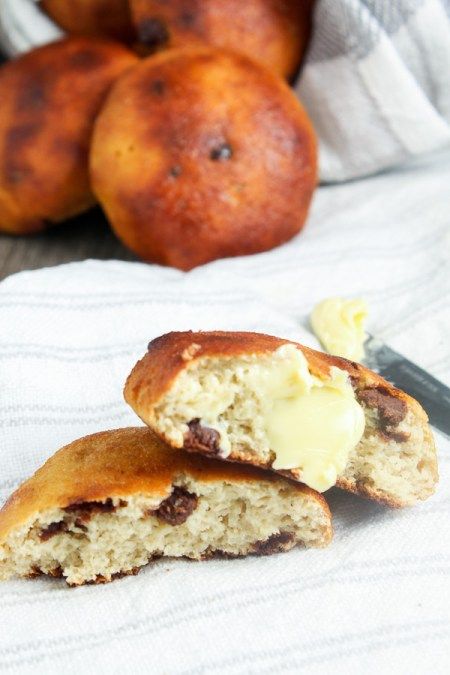 two pieces of bread sitting on top of a white towel next to some buns