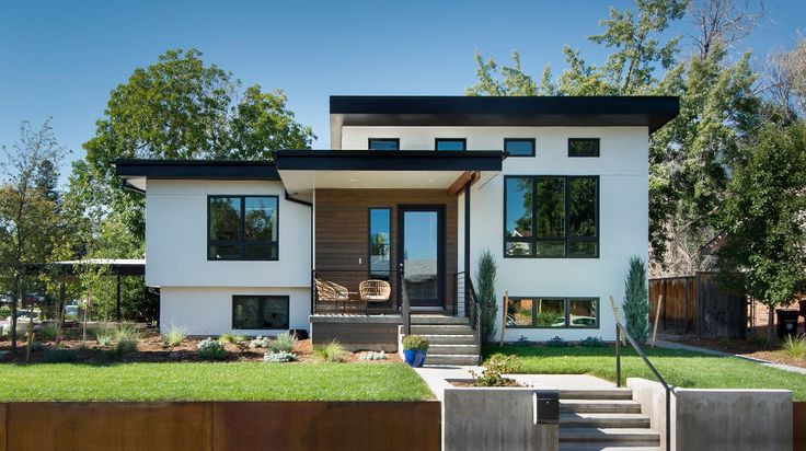 a modern house with grass and trees in the background