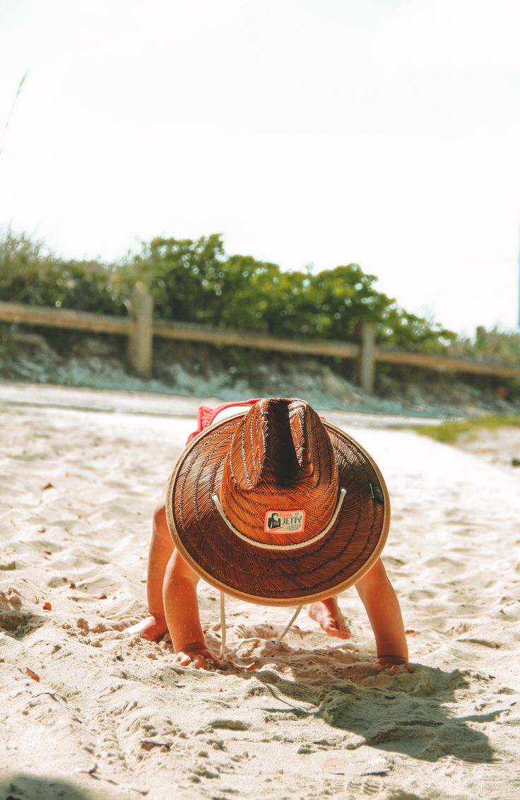 a small child on the beach wearing a hat