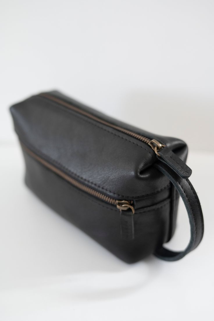 Natural grain leather toiletry bag, lined with cotton fabric. Wide-open interior for easy access to toiletries and other daily essentials. Featuring two zippered exterior pocket. Black Leather Travel Cosmetic Bag, Classic On-the-go Cosmetic Bag With Zipper, Black Leather Cosmetic Bag, Classic Black Cosmetic Bag For Everyday Use, Leather Travel Cosmetic Bag With Zipper Pocket, Leather Cosmetic Bag With Zipper Pocket For Travel, Leather Travel Cosmetic Bag With Zipper, Classic Soft Leather Travel Pouch, Black Leather Cosmetic Bag With Zipper