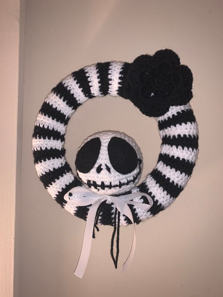 a black and white knitted wreath with a skull in the middle hanging on a wall