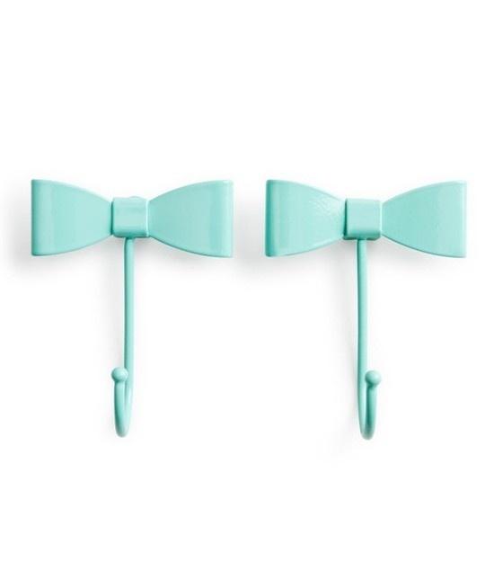 two mint green bow - tie hooks hang on the wall in front of a white background