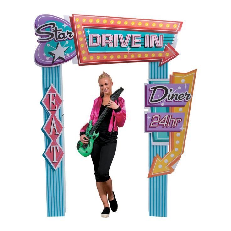 a woman holding a guitar standing under a drive in sign