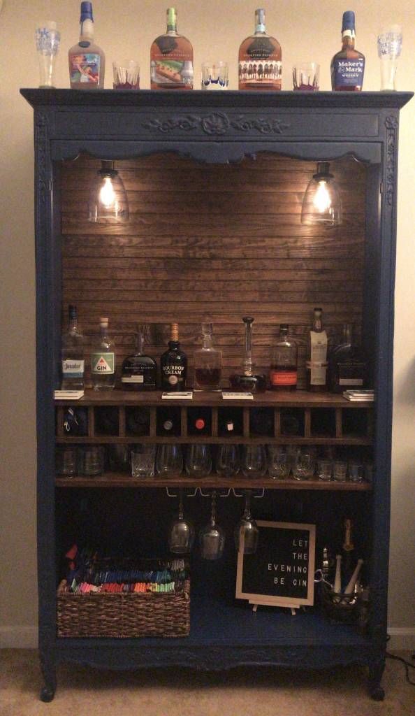 an old fashioned bar with liquor bottles and glasses on it's top shelf, lit by lights