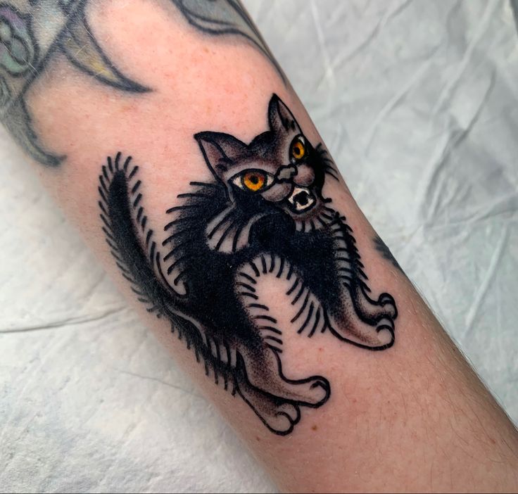 a black and white cat tattoo on the arm with yellow eyes in front of it