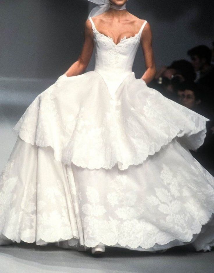 a woman in a white wedding dress on a runway