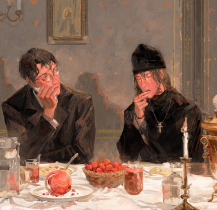 two people sitting at a table with food in front of them and one person holding his hand to his mouth