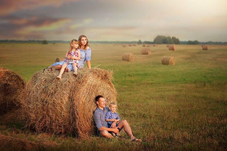 a family sitting on hay bales in a field