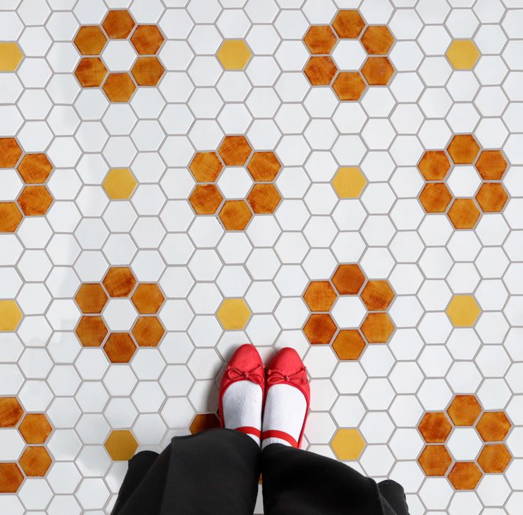 someone's feet in red and white shoes on a tiled floor with hexagonal tiles