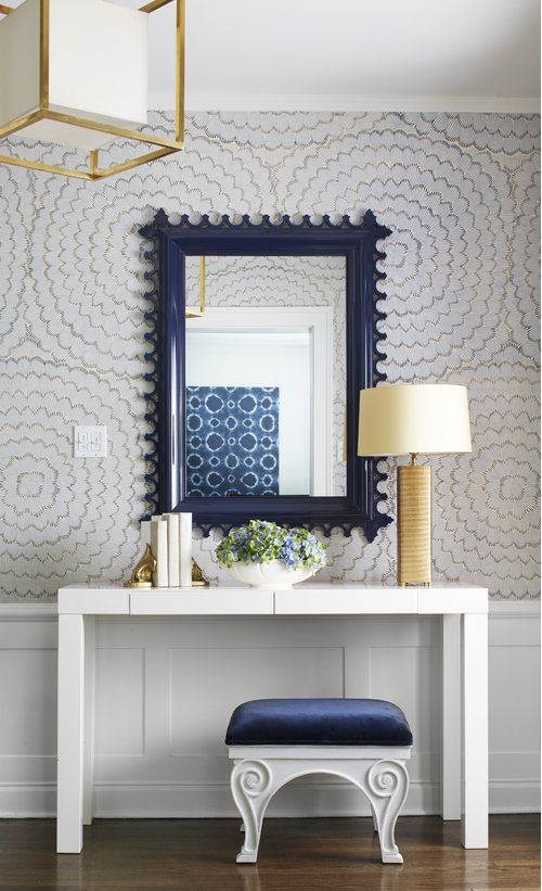 a white table with a blue chair and mirror on top of it next to a lamp