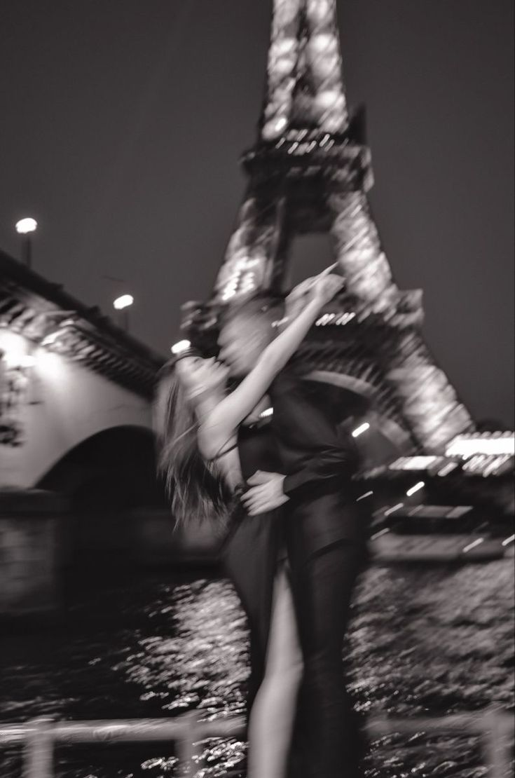 two people are dancing in front of the eiffel tower