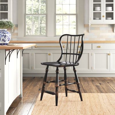 a black chair sitting on top of a hard wood floor in a kitchen next to an island