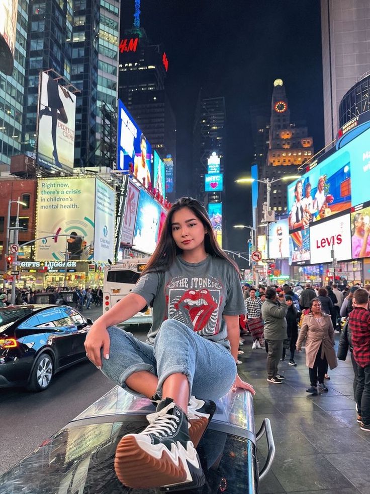 a young woman sitting on top of a skateboard in the middle of a city