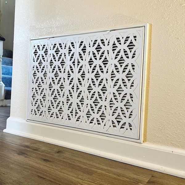 a close up of a white decorative panel on the wall next to a wood floor