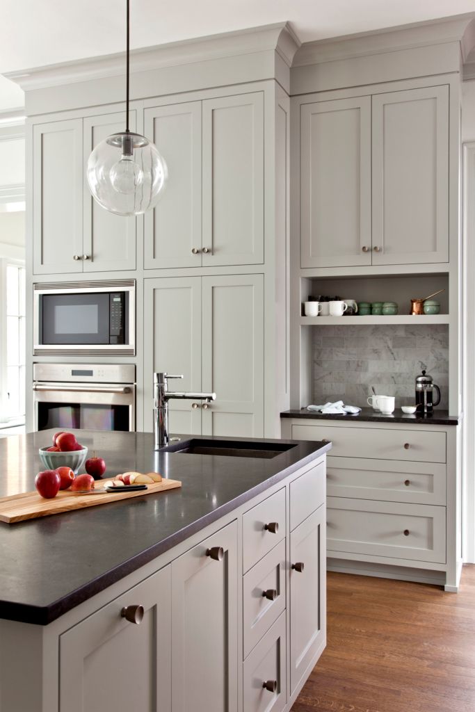 a kitchen with white cabinets and black counter tops, an island in the middle has apples on it