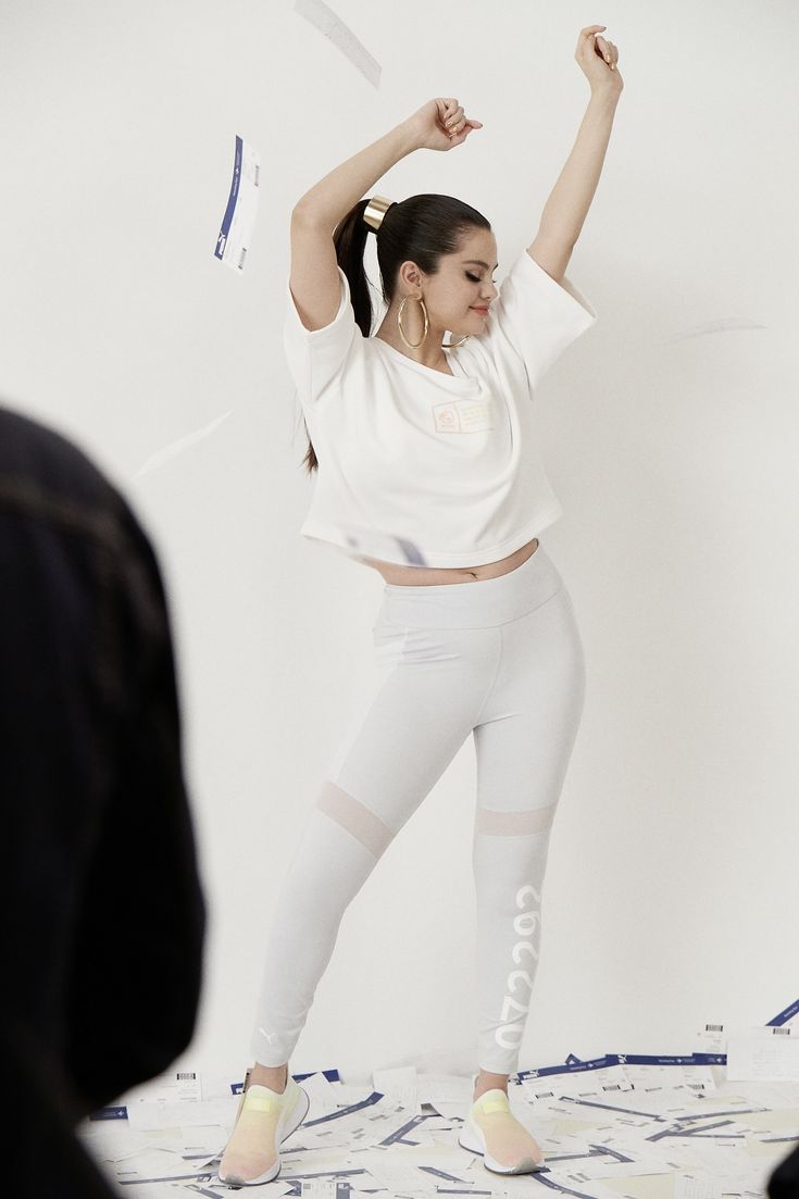 a woman standing on top of a bed with her arms in the air