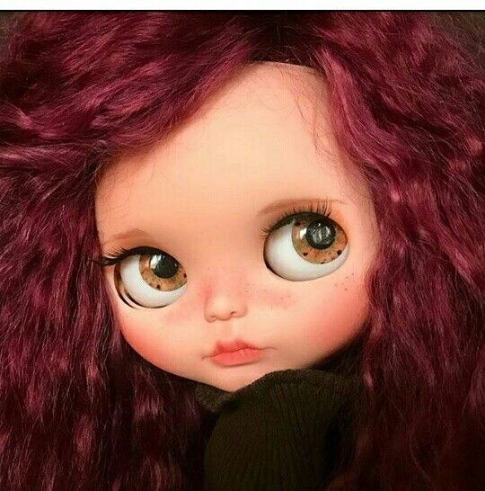 a close up of a doll with red hair and big eyes wearing a black sweater