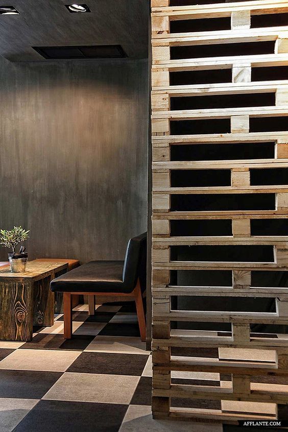 a room with black and white checkered flooring, wooden walls and tables in it