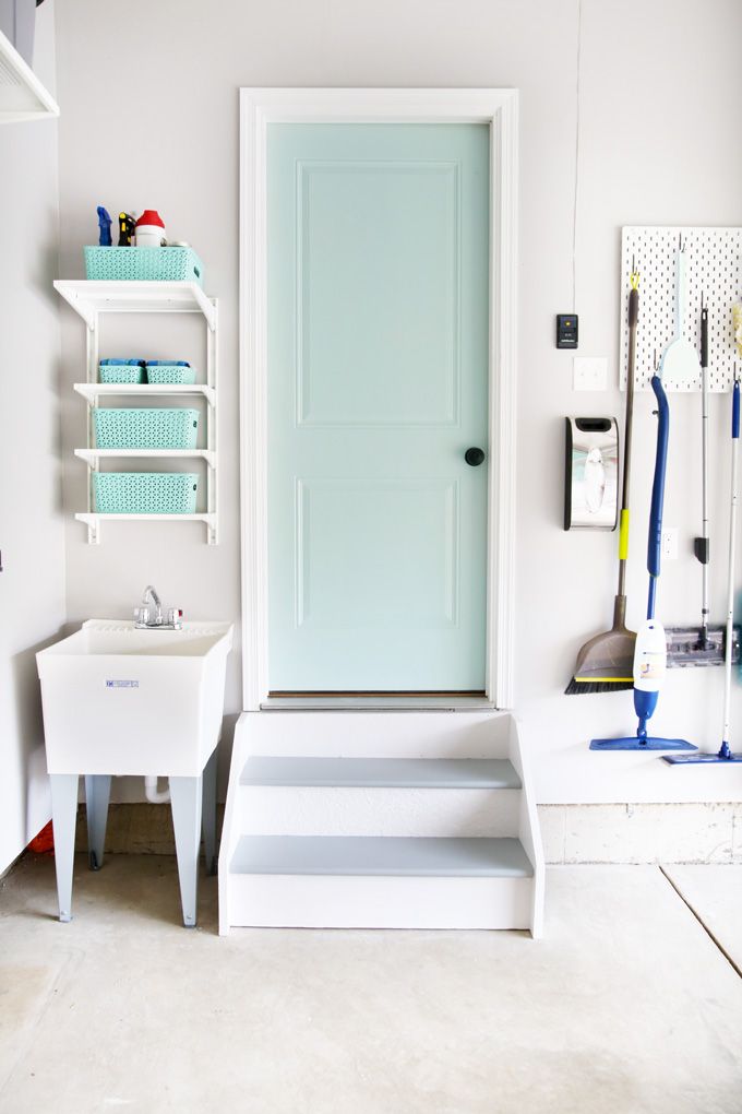 a white room with a blue door and some shelves on the wall next to it