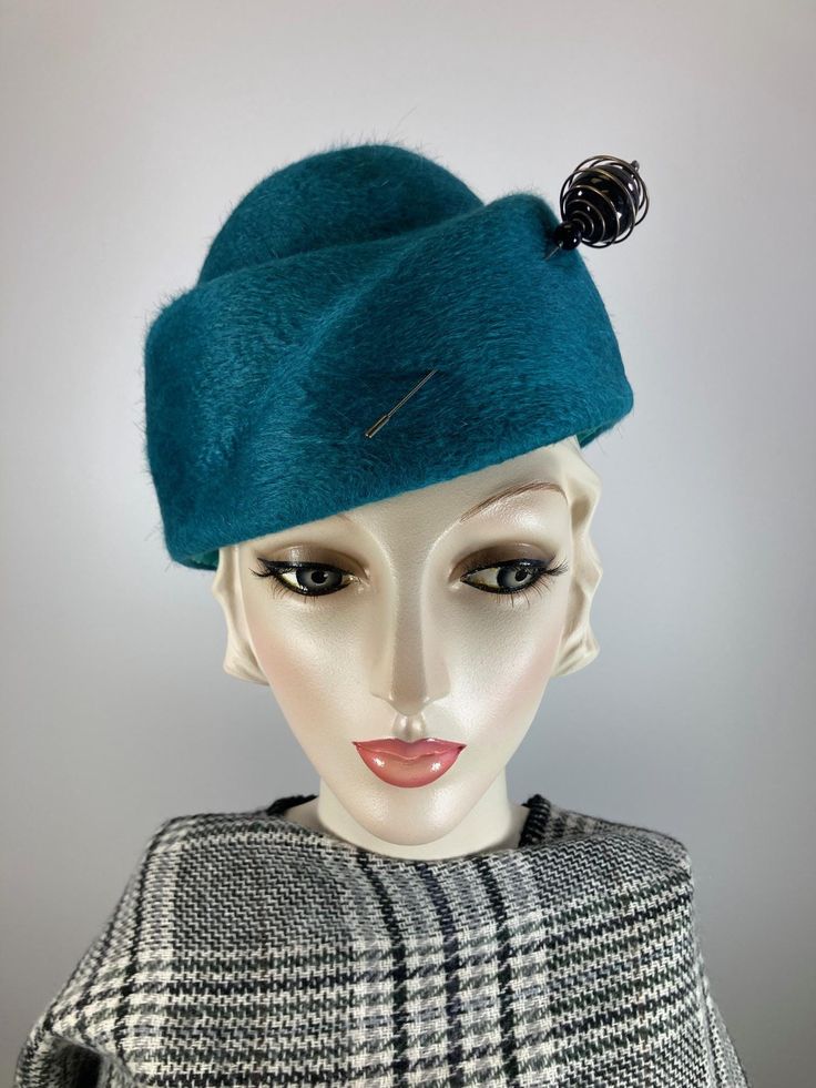 This military inspired women's hat is a statement. It's handmade and hand blocked on a vintage hat block. The hat is a pretty teal/turquoise wool felt and is simply embellished with a black and silver metal hat pin that accentuates the hat's lines and gives it a distinctly vintage vibe. The hat was re-blocked from a piece of recycled wool felt. Great for fall and winter - you'll turn heads with this little number. Wear it casually or dress it up with a Pea Coat. Completely hand made and one of a kind. An adjustable inner grosgrain ribbon helps keep makeup off of the hat and it fits a 22 to 24 inch head size..  In stock and ready to ship. FIT AND SIZE: Comfortably fits a 22  to 24 inch head size.  HOW TO MEASURE YOUR HEAD SIZE: Place a flexible tape measure around the widest part of your he Winter Military Hat With Curved Brim, Green Military Hat With Wide Brim, Navy Pillbox Hat, London In March, Garrison Cap, Green Military Cotton Hat, Vintage Military Visor Hat, Army Hat, Hat Blocks