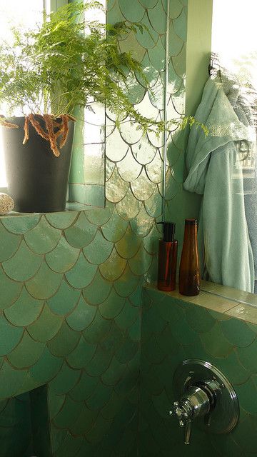 a green tiled bathroom with plants in the window sill