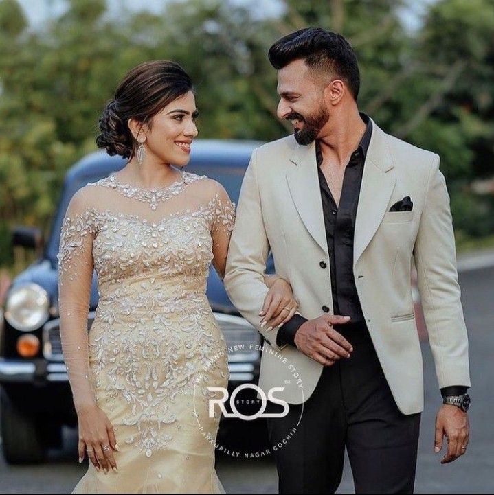 a man and woman are walking together in front of a car