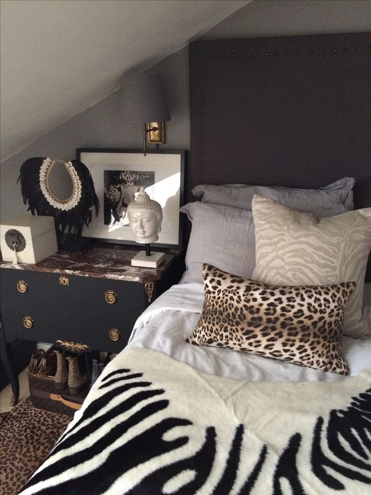 a bedroom with a zebra print blanket on the bed and black dresser next to it