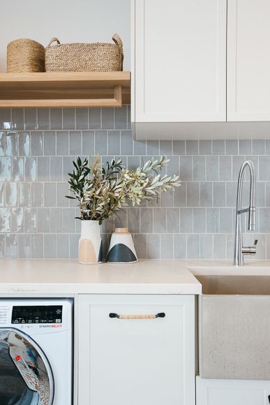 a washer and dryer sitting in a kitchen next to a counter with baskets on it