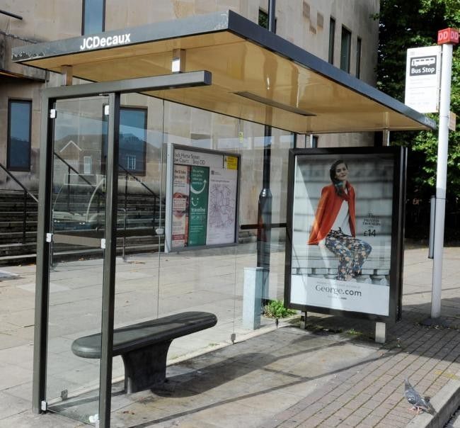 a bus stop with a bench on the sidewalk